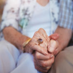 A close up of an elderly couple holding hands.
