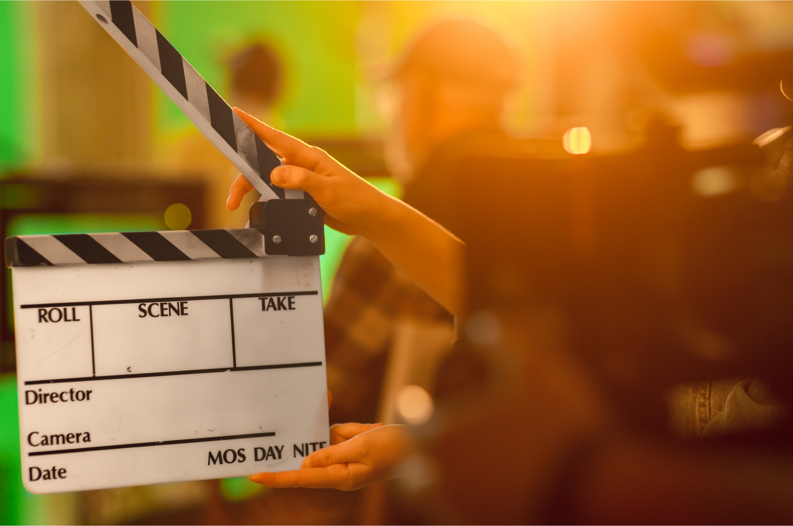 A clapperboard being held up in front of a green screen.